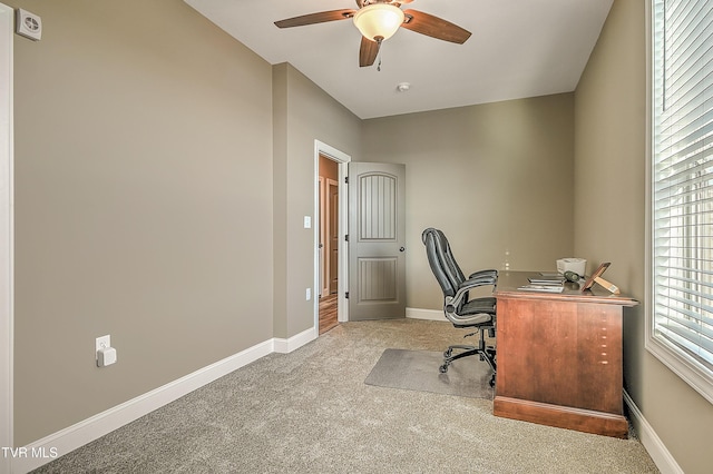 office space featuring light carpet, a ceiling fan, and baseboards