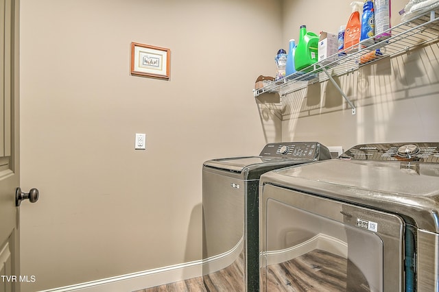 clothes washing area with laundry area, wood finished floors, baseboards, and washer and clothes dryer