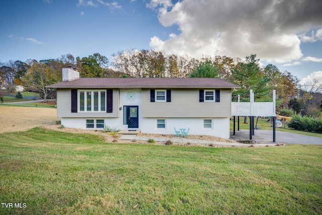 raised ranch featuring a front yard and a chimney