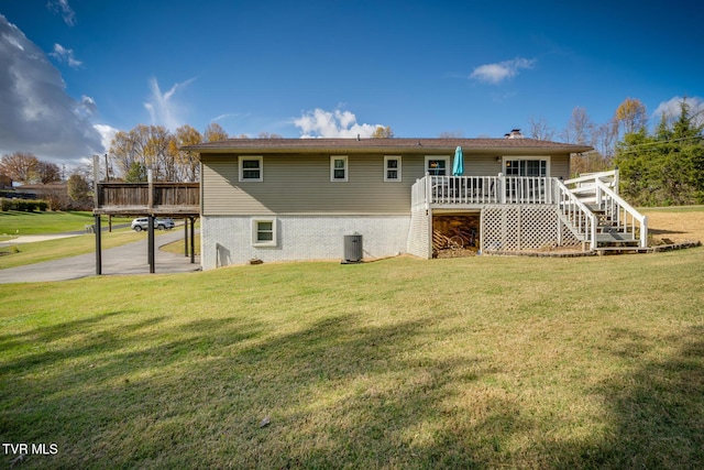 back of property with brick siding, a wooden deck, stairs, central AC unit, and a yard