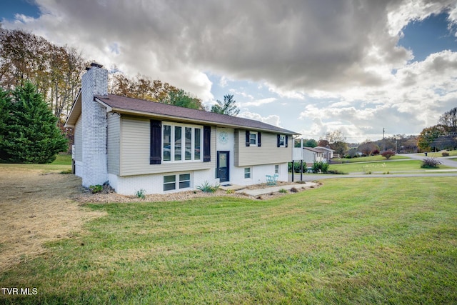 raised ranch featuring brick siding, a chimney, and a front yard