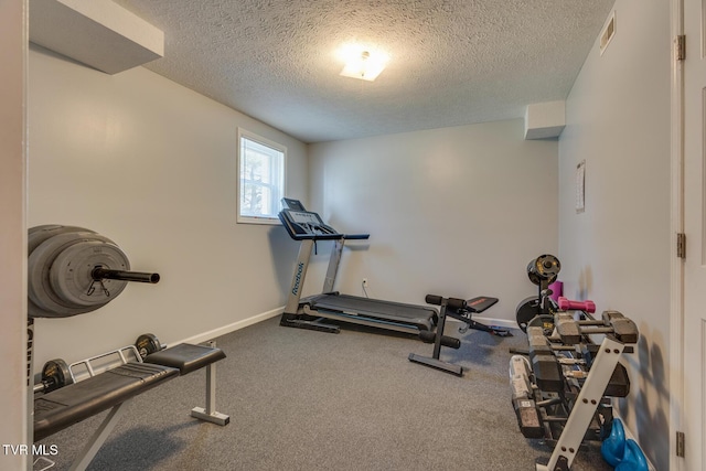 exercise area featuring visible vents, a textured ceiling, and baseboards