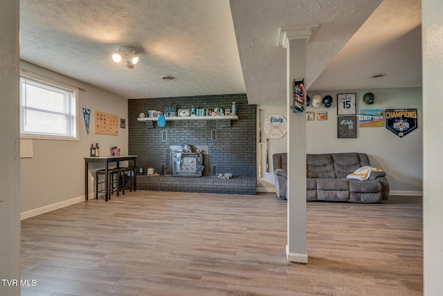 living area with baseboards, wood finished floors, and a wood stove