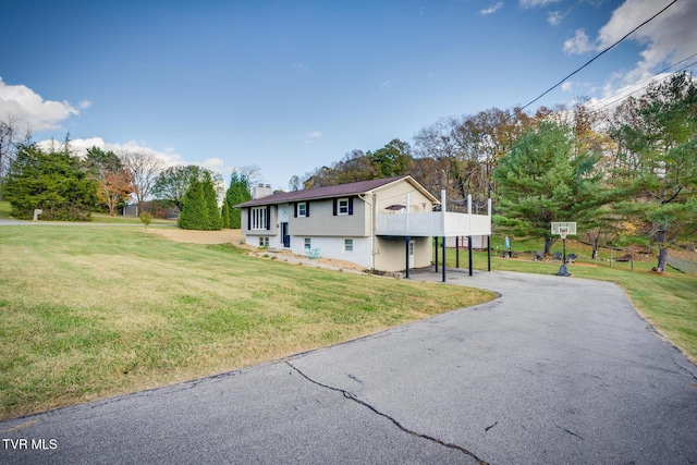 view of front of property with aphalt driveway, a chimney, and a front yard