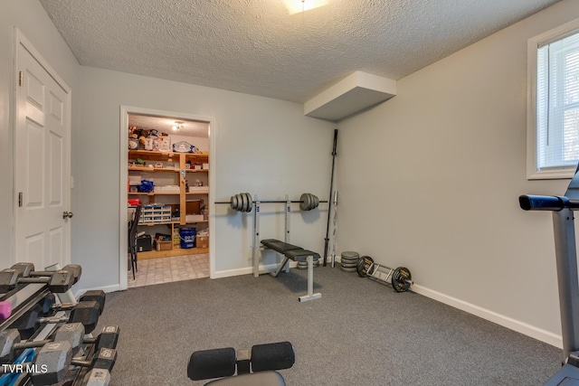 workout area featuring baseboards, carpet floors, and a textured ceiling