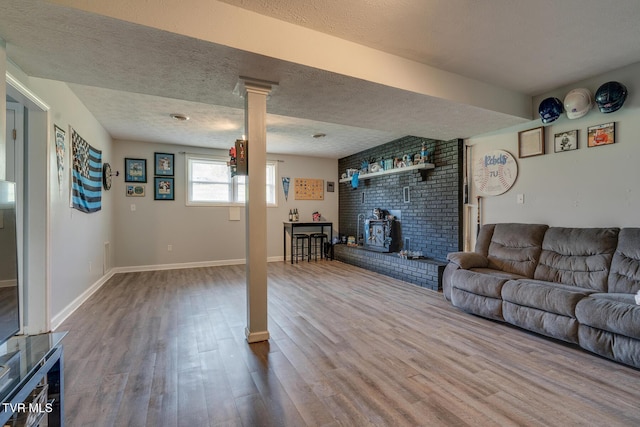 unfurnished living room featuring dark wood-style floors, a textured ceiling, a wood stove, and baseboards