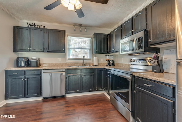 kitchen featuring crown molding, dark wood finished floors, stainless steel appliances, a textured ceiling, and a sink