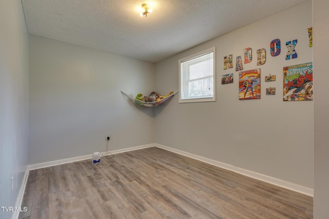 spare room with a textured ceiling, baseboards, and wood finished floors