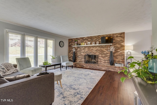 living room with a brick fireplace, a textured ceiling, wood-type flooring, and ornamental molding