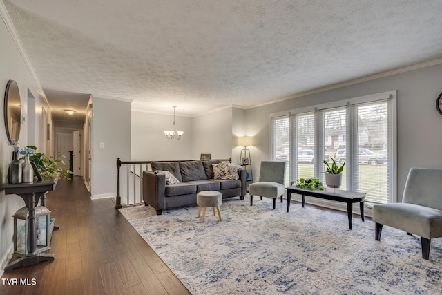 living room featuring dark wood-style floors, a chandelier, a textured ceiling, and ornamental molding