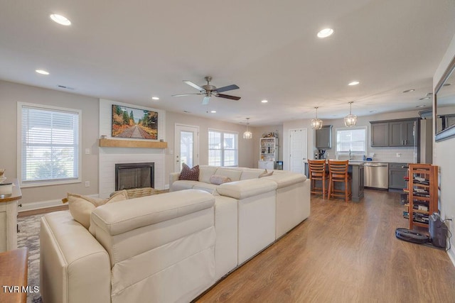 living room featuring recessed lighting, a brick fireplace, and wood finished floors