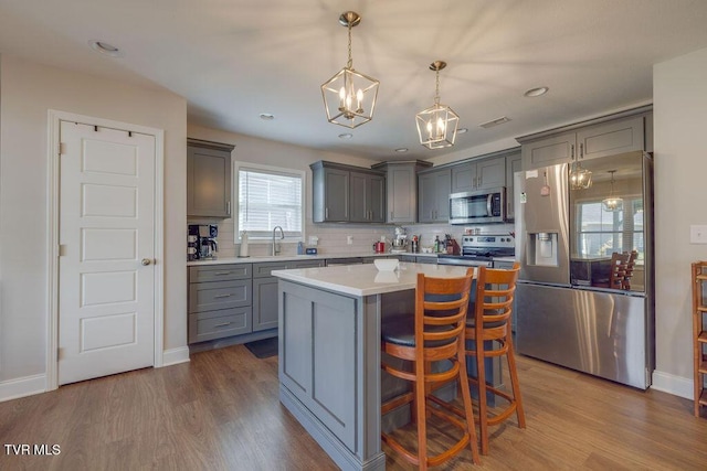 kitchen with a center island, dark wood-type flooring, gray cabinetry, and stainless steel appliances