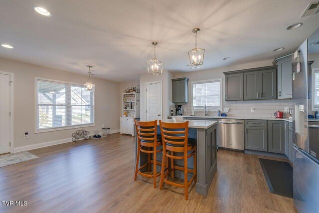 kitchen featuring visible vents, gray cabinetry, a center island, dishwasher, and dark wood-style flooring