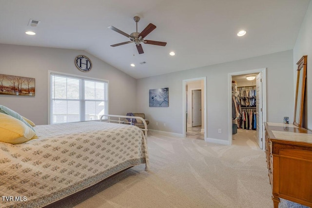 bedroom featuring baseboards, visible vents, lofted ceiling, a spacious closet, and light carpet