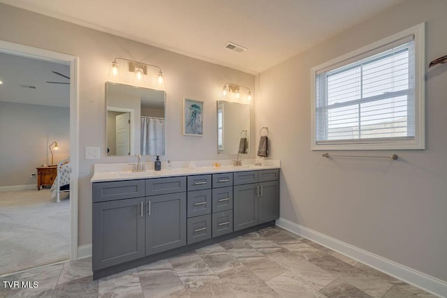 bathroom with ensuite bath, double vanity, baseboards, and a sink