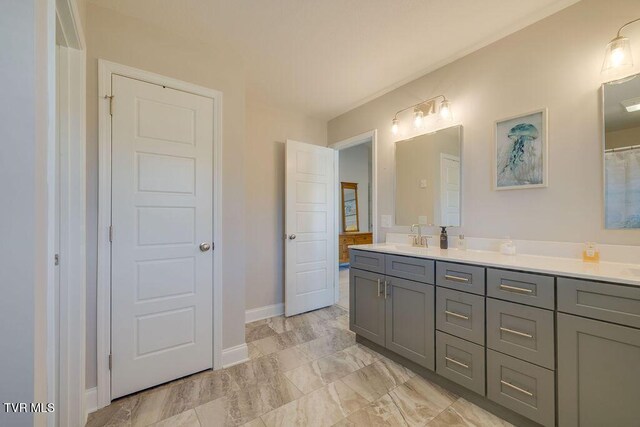 bathroom with double vanity, baseboards, marble finish floor, and a sink