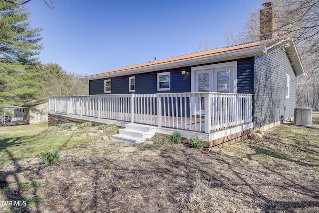 view of front of house featuring a deck, central AC, and a chimney