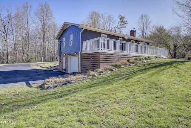 view of home's exterior with aphalt driveway, a chimney, a deck, a yard, and an attached garage