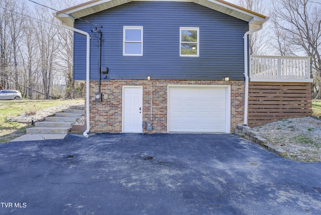 view of side of property with aphalt driveway, stairway, an attached garage, and brick siding