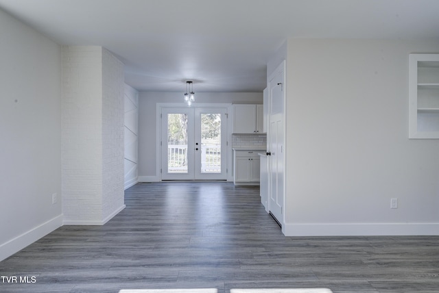 empty room featuring dark wood finished floors, french doors, and baseboards