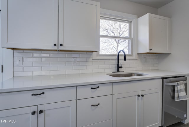 kitchen featuring a sink, light countertops, white cabinets, stainless steel dishwasher, and tasteful backsplash