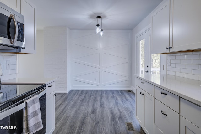 kitchen with visible vents, electric stove, stainless steel microwave, wood finished floors, and light countertops