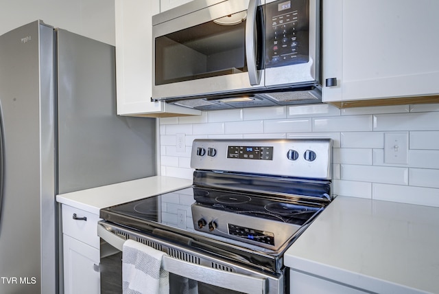 kitchen with stainless steel appliances, backsplash, light countertops, and white cabinetry