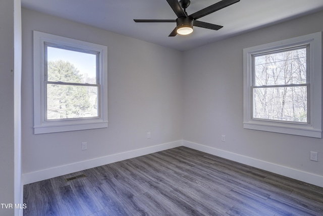 spare room with dark wood finished floors, visible vents, ceiling fan, and baseboards