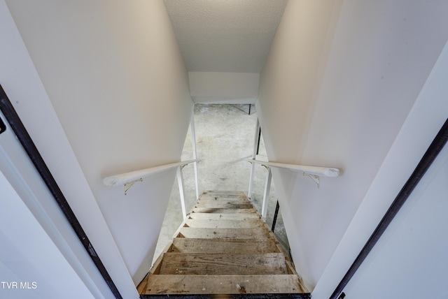 staircase with a textured ceiling