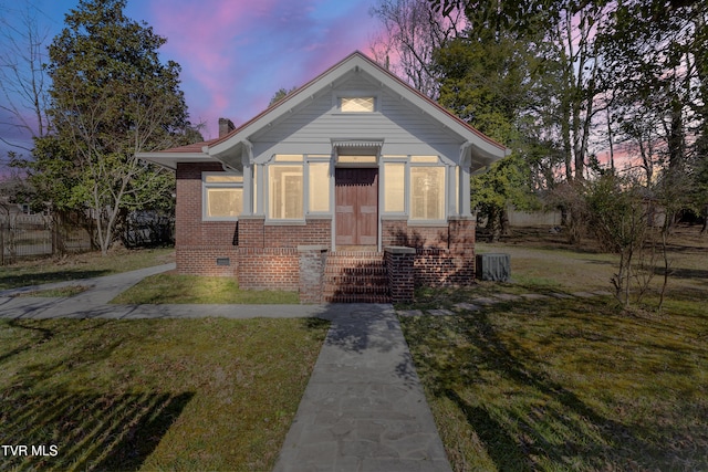 bungalow-style home with a front yard, cooling unit, brick siding, and crawl space