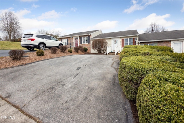 ranch-style home featuring aphalt driveway and brick siding