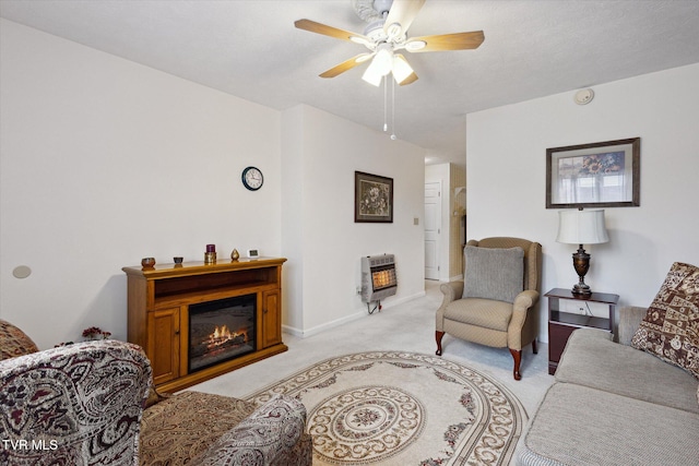 living room with heating unit, a glass covered fireplace, light carpet, and a ceiling fan