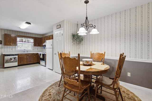 dining area featuring a chandelier, wallpapered walls, and baseboards