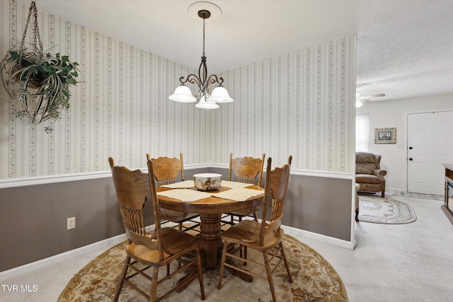 carpeted dining room featuring baseboards, wallpapered walls, and an inviting chandelier