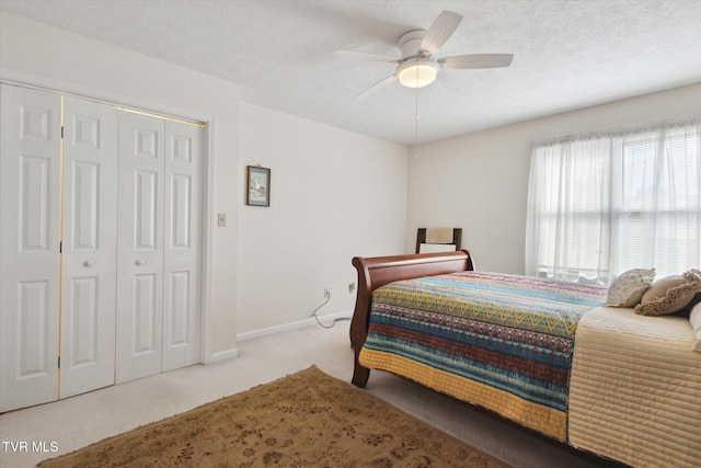 bedroom with a textured ceiling, a closet, carpet floors, baseboards, and ceiling fan