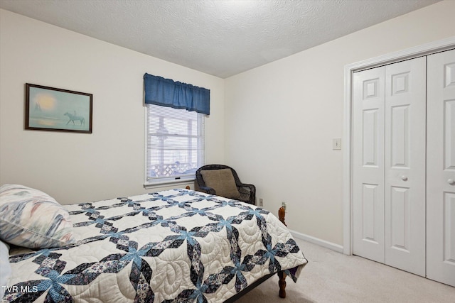 bedroom featuring a textured ceiling, baseboards, a closet, and light carpet