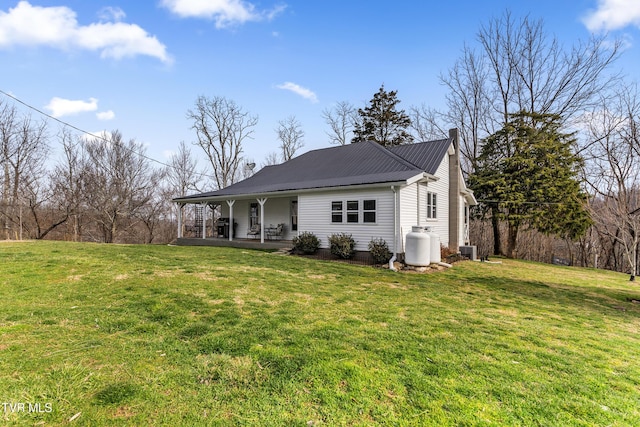 view of front of house with metal roof, a front yard, a porch, and a chimney