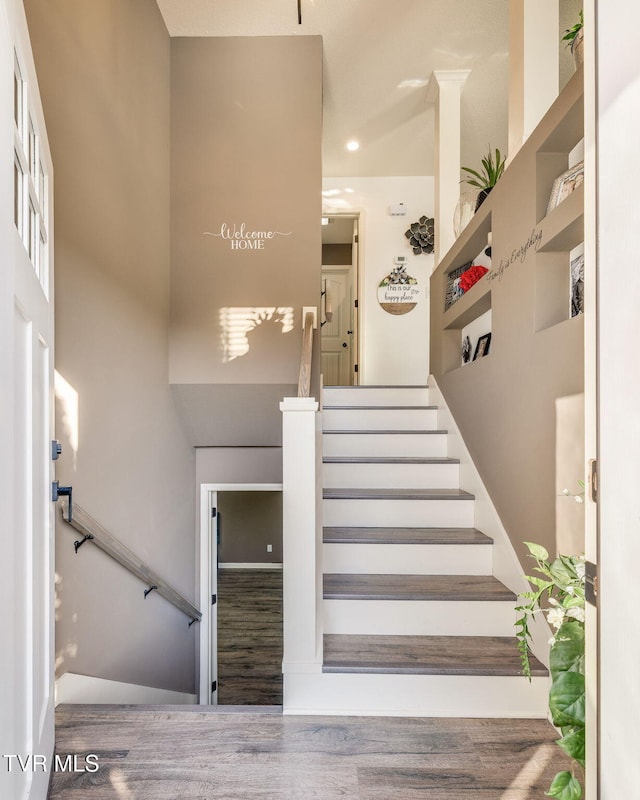 stairway featuring a high ceiling and wood finished floors