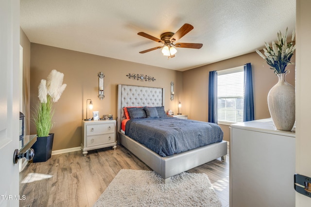 bedroom with ceiling fan, a textured ceiling, baseboards, and wood finished floors