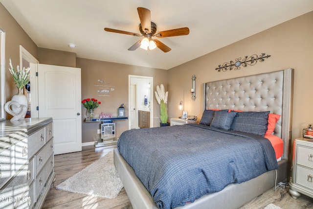 bedroom with a ceiling fan, wood finished floors, baseboards, and connected bathroom