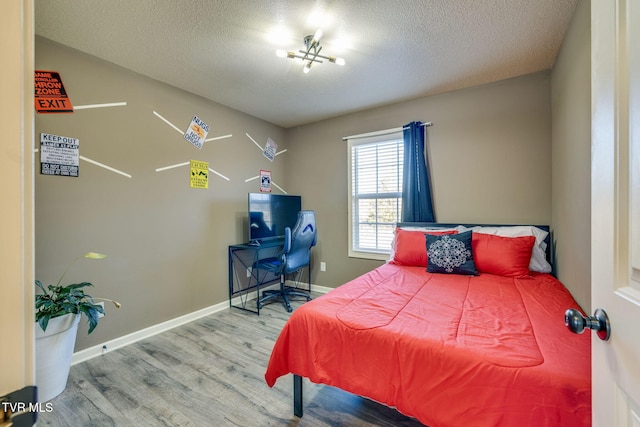 bedroom featuring a textured ceiling, baseboards, and wood finished floors