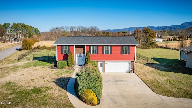 split foyer home with a mountain view, concrete driveway, a front lawn, and fence