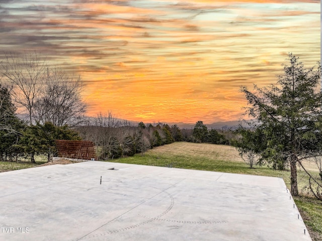 patio terrace at dusk featuring a yard