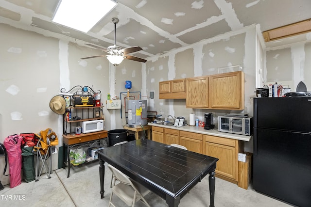 kitchen featuring white microwave, light countertops, water heater, freestanding refrigerator, and a sink