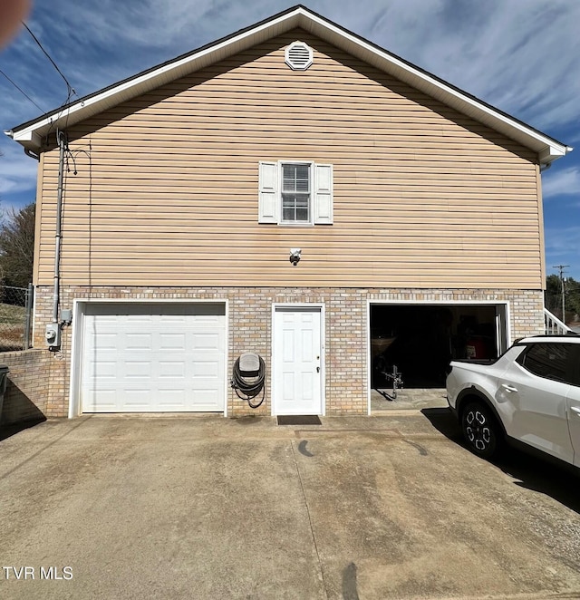 view of home's exterior with an attached garage, brick siding, and driveway