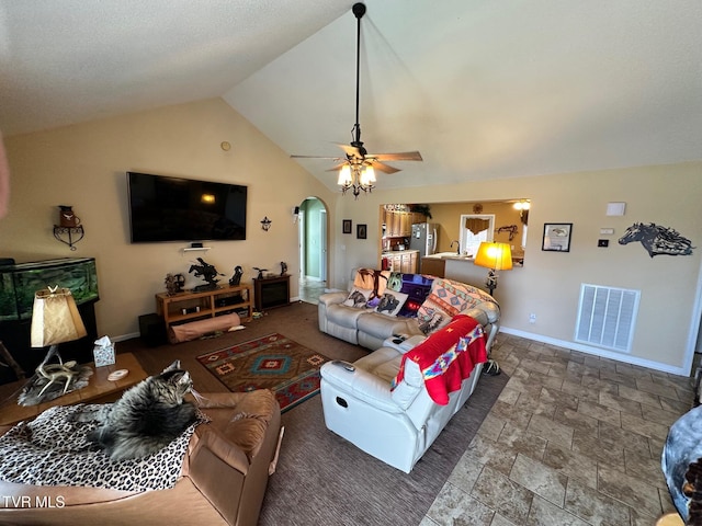 living room with visible vents, baseboards, vaulted ceiling, arched walkways, and stone finish floor