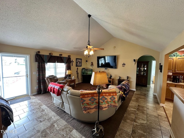 living room featuring stone finish flooring, baseboards, vaulted ceiling, arched walkways, and a textured ceiling