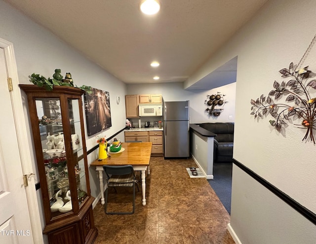 kitchen with white microwave, baseboards, recessed lighting, freestanding refrigerator, and light countertops