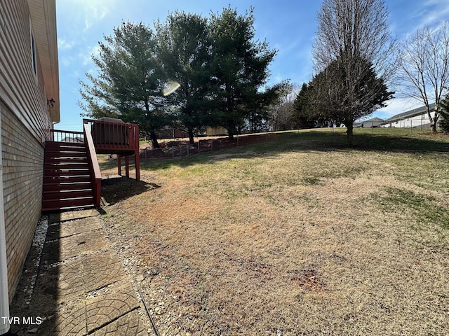 view of yard with a deck, stairs, and fence