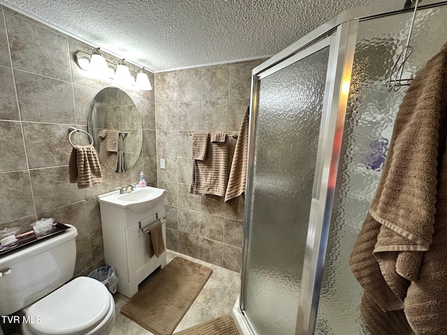 bathroom with vanity, a shower stall, a textured ceiling, tile walls, and toilet